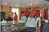 People browsing clothing racks inside a small retail store with display cases and posters.