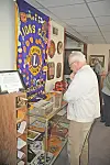 Man standing beside a glass display case and Lions Club banner, looking at memorabilia.
