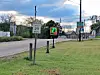 Digital speed display reading 27 beside a 25 mph sign along a road.