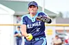 Softball pitcher in blue uniform preparing to throw a yellow ball during a game.