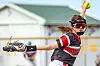 Softball pitcher in a red and black uniform throwing a pitch.