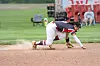 Baseball player stretches forward on the infield dirt to field a ground ball.