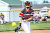 Softball pitcher in black and red uniform throws a pitch on a field.