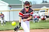 Softball pitcher in black and red uniform throws a pitch on a field.