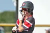 Softball player in a helmet and gloves standing at bat.