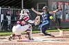 Softball player slides into home plate while the catcher reaches for the tag.
