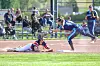 A softball runner slides into home plate while a catcher reaches to apply a tag.