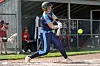 Softball batter swings at a pitch near home plate during an outdoor game.