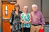 Three people standing indoors in front of a door and wall at a hospice.