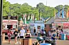 People gathered near food stalls and booths at an outdoor fairground.