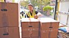 Worker in a safety vest handling stacked fragile boxes in a warehouse loading area.