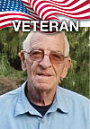 Elderly man in glasses and a blue shirt under a U.S. flag graphic with the word veteran.