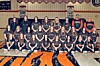 A girls basketball team poses for a group photo in a gym with banners and a tiger logo on the floor.