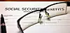 Social Security benefits application form with eyeglasses and a pen on a desk.