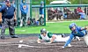 Two baseball players slide toward a base while an umpire watches on a baseball field.