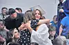 A graduate in a cap and gown hugs a guest during a commencement ceremony.