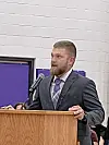 A man in a suit speaking at a podium with a microphone indoors.