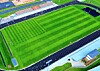 Aerial view of a green stadium field with stands, track lines, and nearby buildings.
