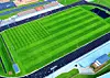 Aerial view of a green stadium field with stands, track lines, and nearby buildings.