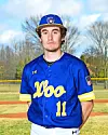 Baseball player in a blue and yellow uniform stands on an outdoor field.