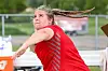 Athlete in a red jersey throwing at an outdoor track and field event.