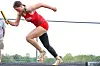 Runner in red and black starting a sprint on a track.