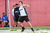 Athlete in a Villanova jersey throws a shot put on a field while others watch in the background.