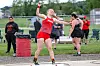 Athlete in red prepares a throw on a field event circle while others watch in the background.