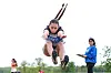 A young athlete is captured mid-jump during an outdoor long jump attempt beside an official.
