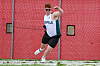 Man in sunglasses and sportswear posing beside a red chain-link fence.