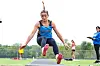 Athlete in blue leaps during a long jump attempt on a track and field runway.