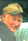Man in a baseball cap looking back from inside a vehicle.