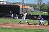 Baseball batter swings as catcher crouches behind home plate on a sunny field.