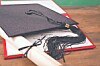 Black graduation cap on top of a diploma and rolled certificate on a wooden table.