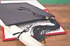 Black graduation cap on top of a diploma and rolled certificate on a wooden table.