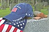 Blue veteran cap with an American flag and a patriotic scarf on a stone ledge.