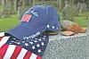 Blue veteran cap with an American flag and a patriotic scarf on a stone ledge.