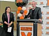 A man stands at a Marlington podium while a woman stands beside him in front of balloon decorations.
