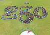 Large group of people arranged to form the number 250 on a grassy field.