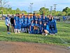 Youth football players and adults posing on a grassy field with a team banner.