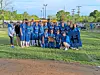 Youth football players and adults posing on a grassy field with a team banner.