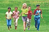 Four children running together across a grassy field.
