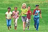 Four children running together across a grassy field.