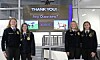Four students stand indoors beside a digital display that says “THANK YOU!” and “Any Questions?”