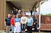 A group of people standing together on a covered porch with wooden railings.