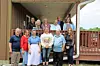A group of people standing together on a covered porch with wooden railings.