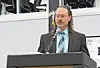 Man speaking at a podium with a microphone in an indoor venue.