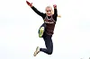 Female runner jumping with arms raised on a white background.