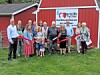 A group poses outside Hartville Hardware with a red ribbon stretched across the front.