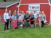 A group poses outside Hartville Hardware with a red ribbon stretched across the front.